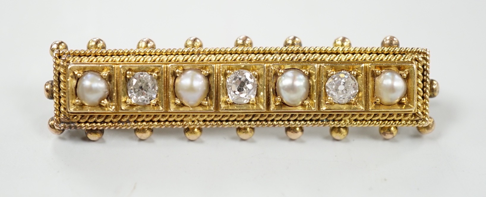 An early 20th century yellow metal, three stone diamond and four stone split pearl set bar brooch, 44mm, gross weight 6.8 grams.